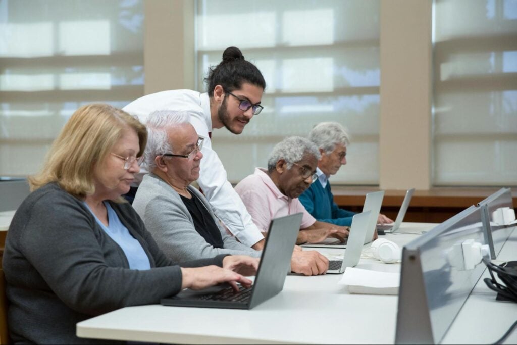 Adult learners using laptops during an instructor-led classroom training session.