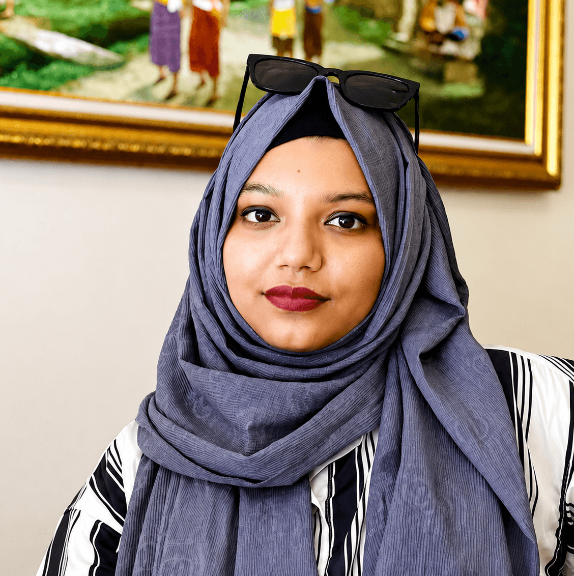 Nadia Akther smiling at the camera while wearing a grey hijab